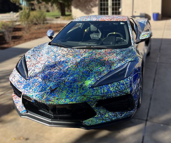 A colorful car is parked on a sidewalk in front of a building.