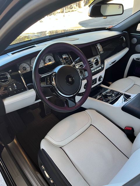 The interior of a car with a purple steering wheel and white seats.