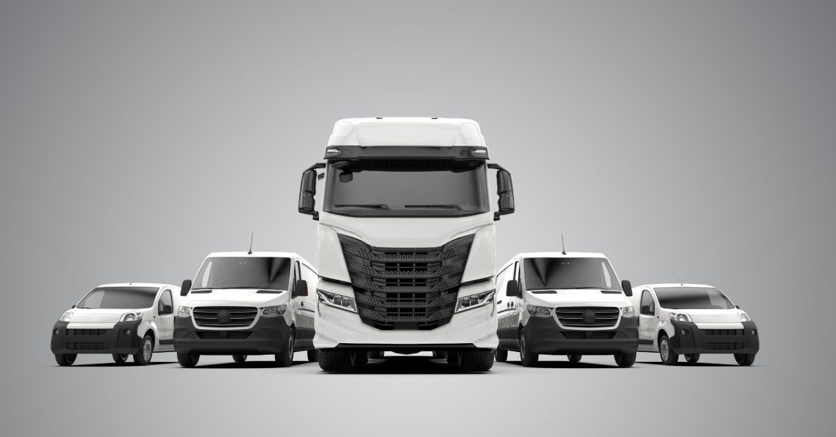 A group of white fleet vehicles like vans line up against a gray background.