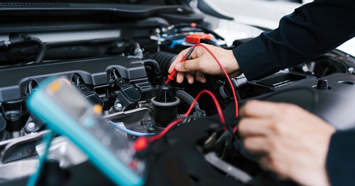 A technician uses a light blue scanner to check the car's electrical system.