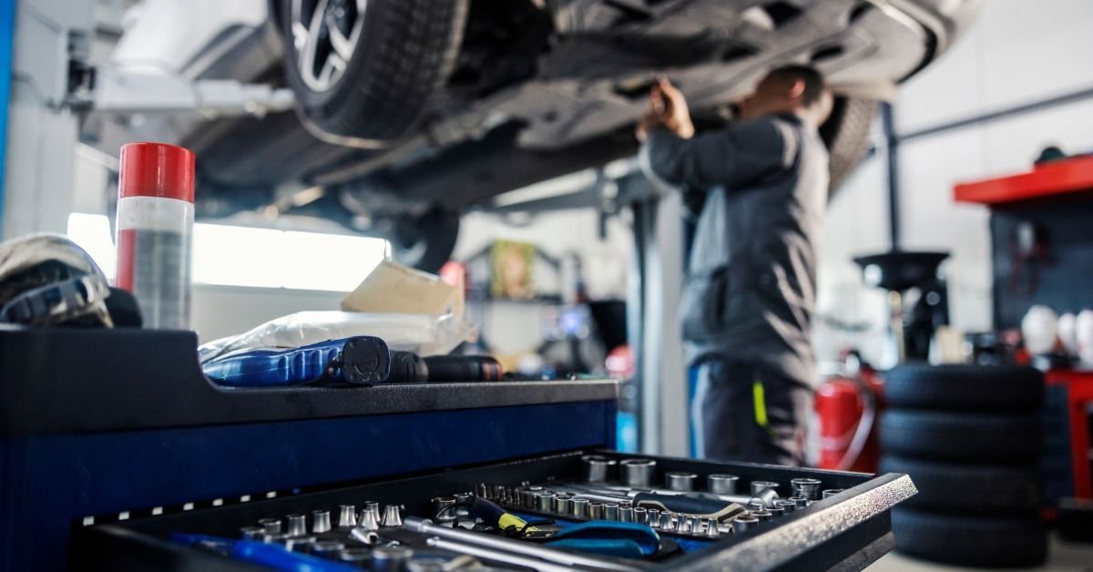  Toolbox in sharp focus, with a blurred mechanic repairing a car behind it.