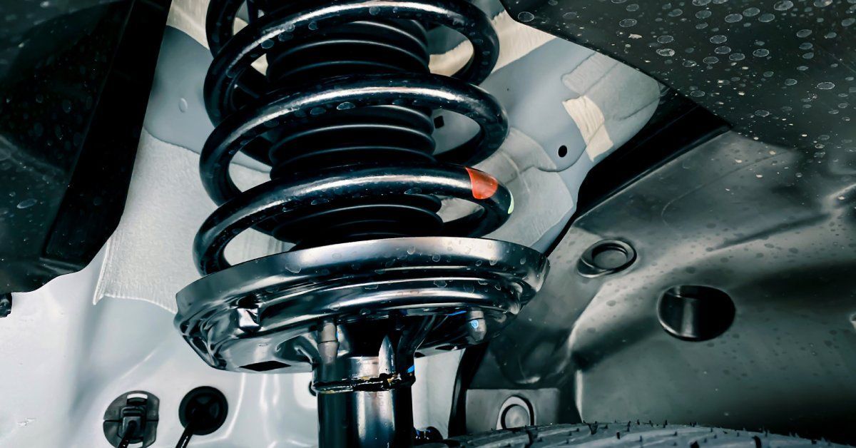 A car's suspension system with a black shock absorber and a coil spring.