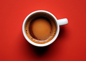 A cup of coffee is sitting on a red table.