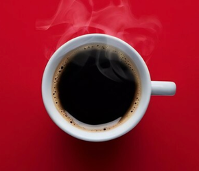 A cup of coffee with steam coming out of it on a red background