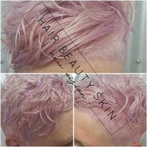 A woman with short pink hair has a shaved head.