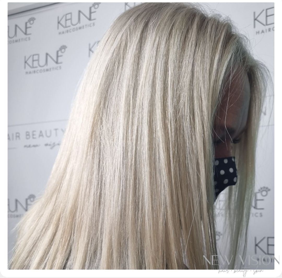 A woman with blonde hair is standing in front of a keune wall