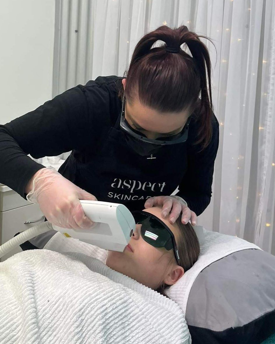 A woman is using a laser on a woman 's face.