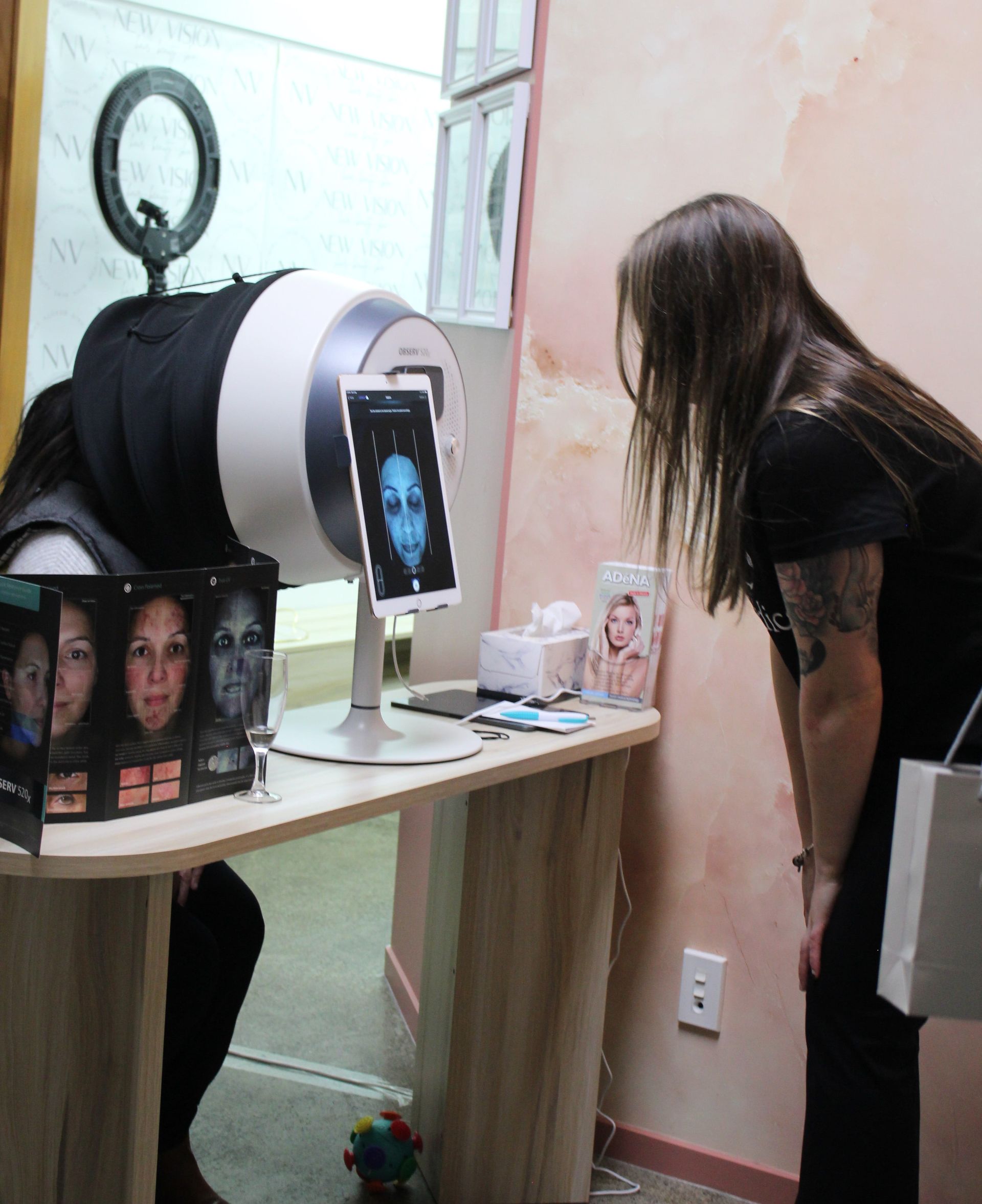 A man in a pink shirt is examining a woman 's face under a magnifying glass.
