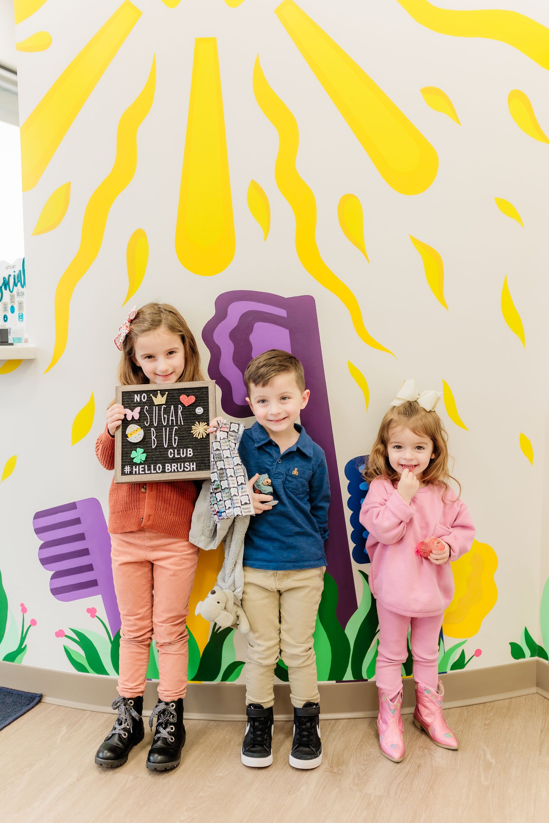 Three children are standing next to each other in a dental office.