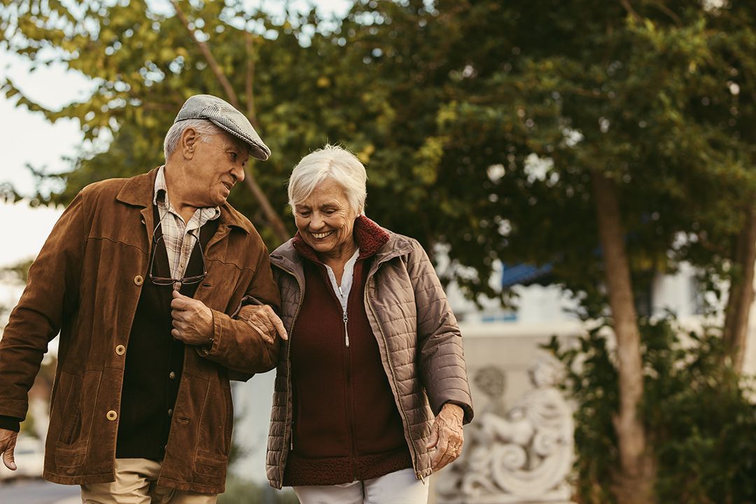 older couple walking arm in arm laughing