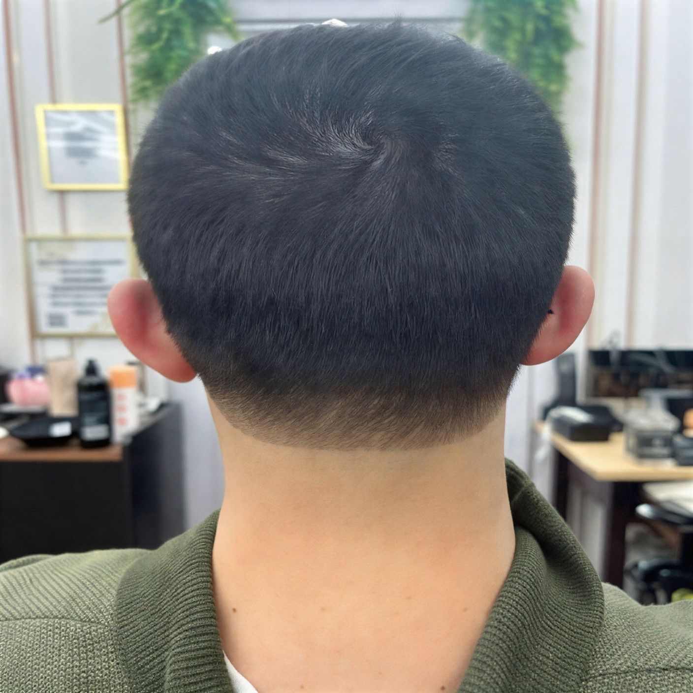 A person's head from the back, showing a close-cropped haircut with a skin fade.