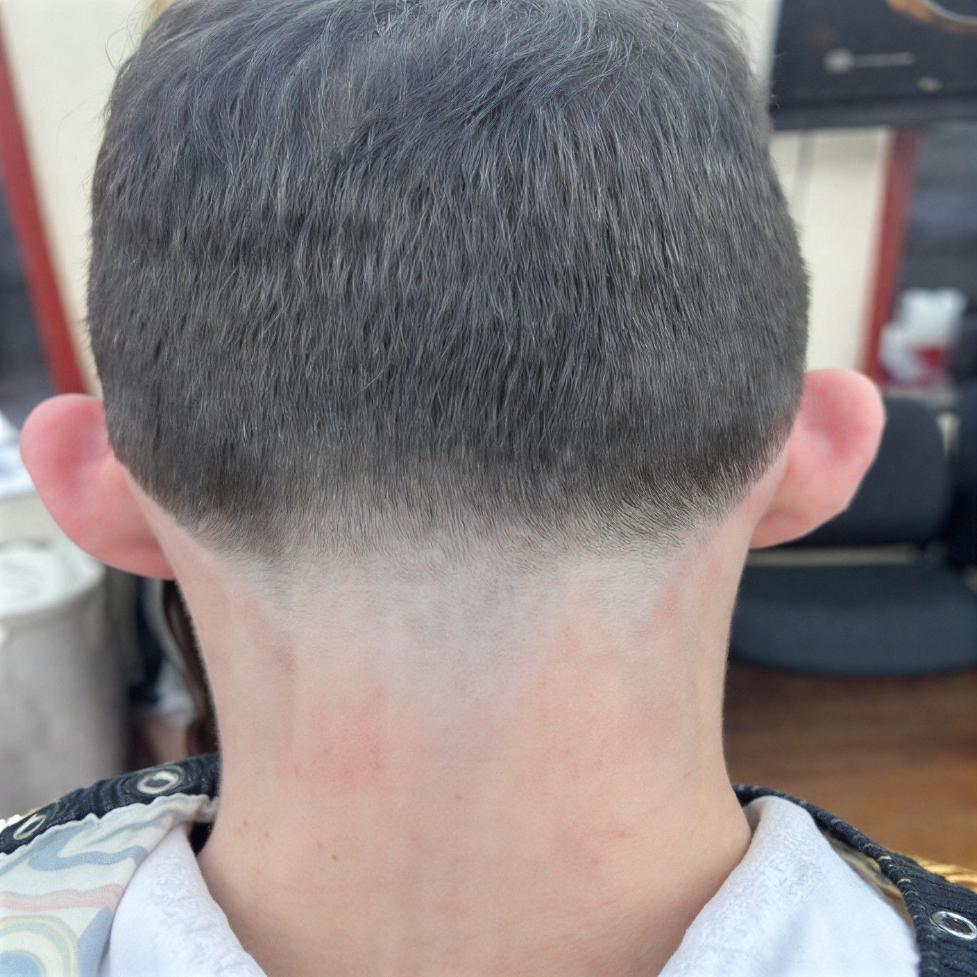 Back of a person's head with a haircut; faded nape and short, dark hair. Light skin.