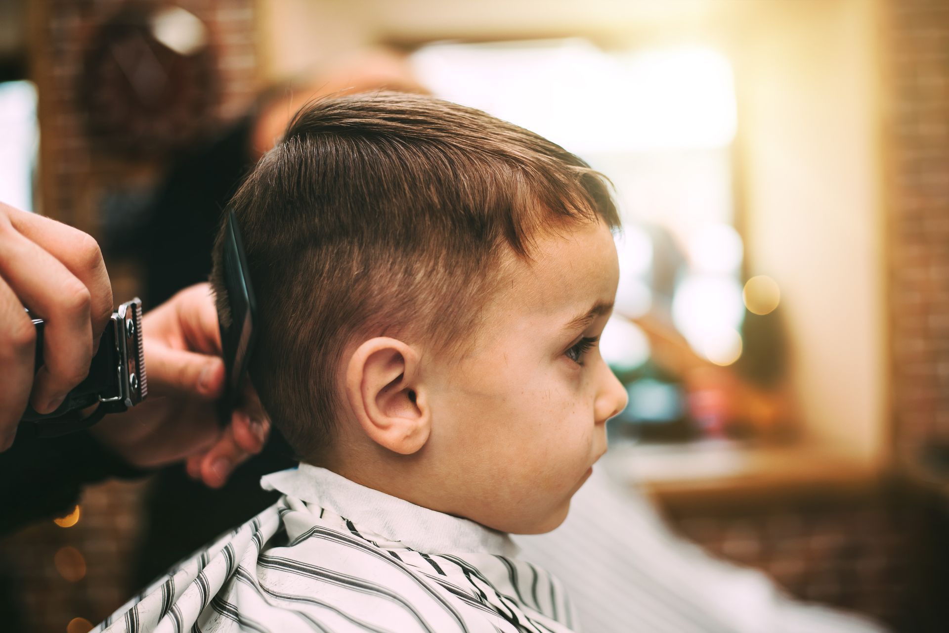 A young boy is getting his hair cut at a barber shop.