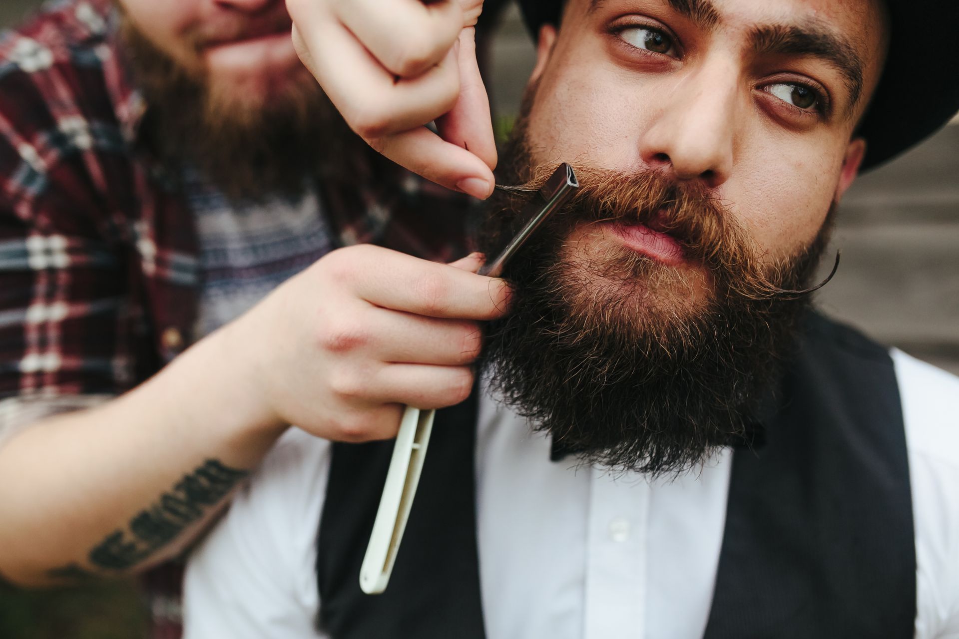 A man is getting his beard trimmed by a barber.
