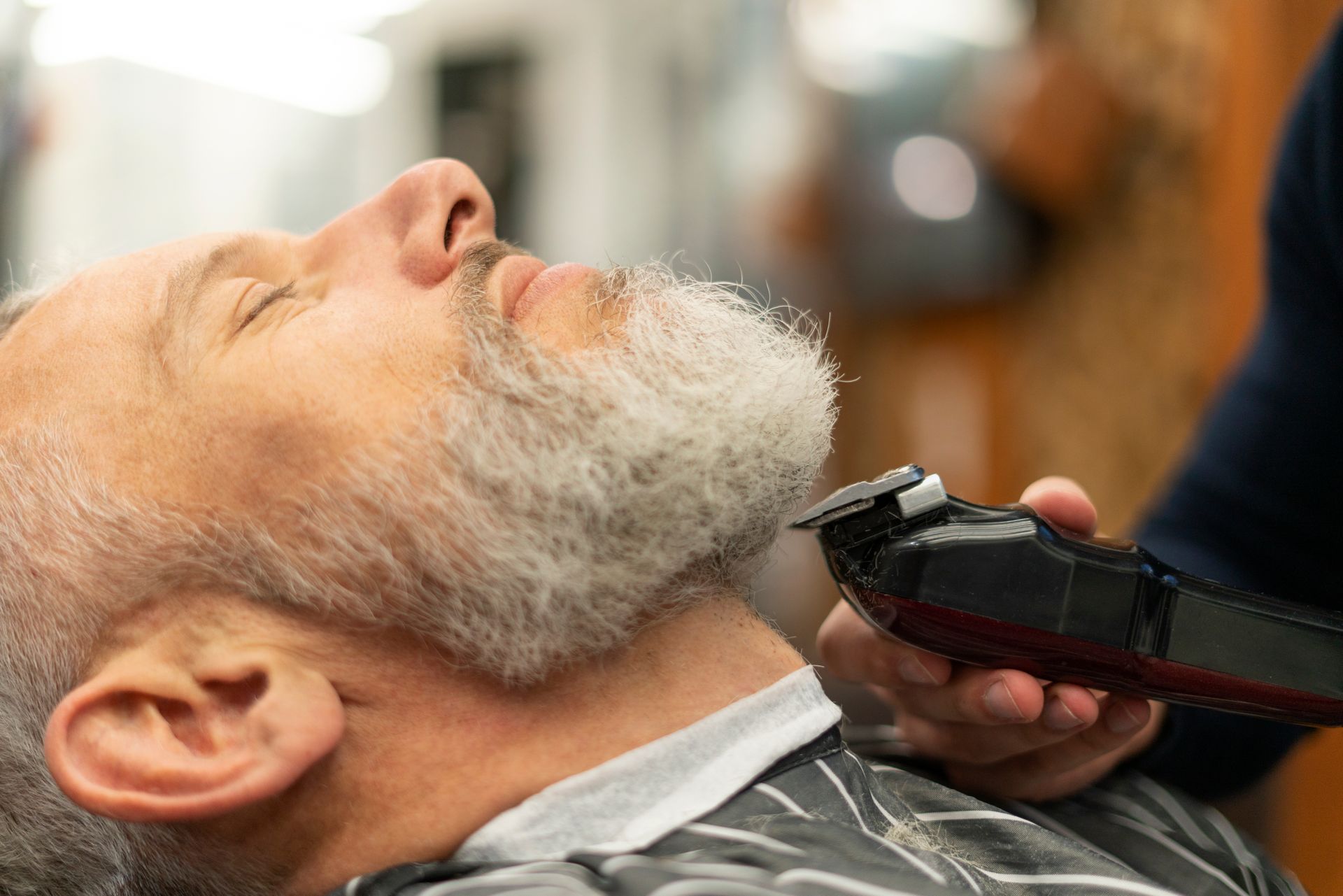 A man is getting his beard shaved at a barber shop.