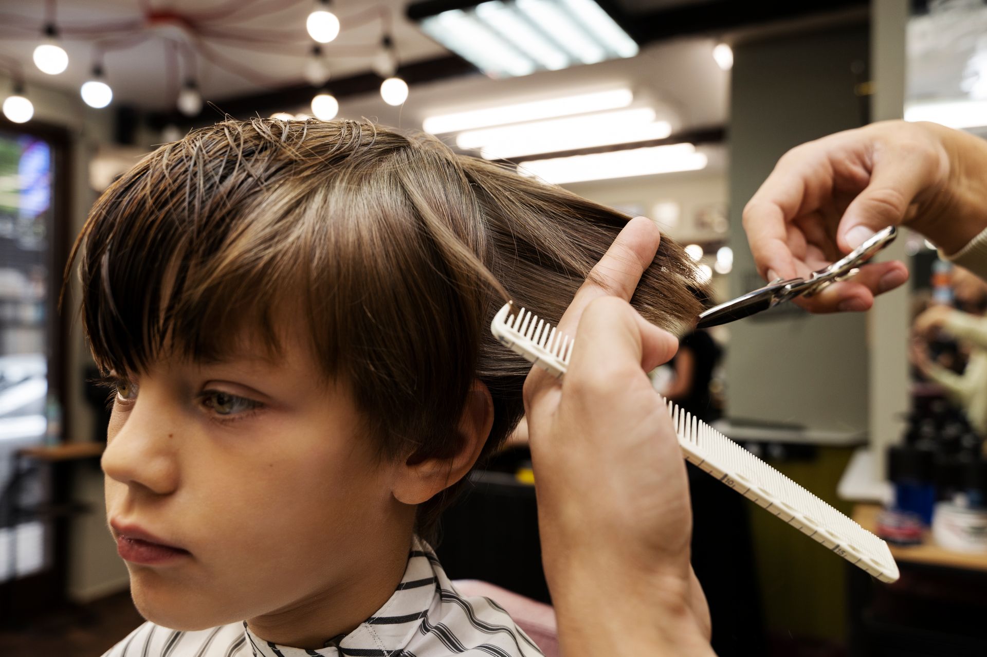 A young boy is getting his hair cut at a barber shop.