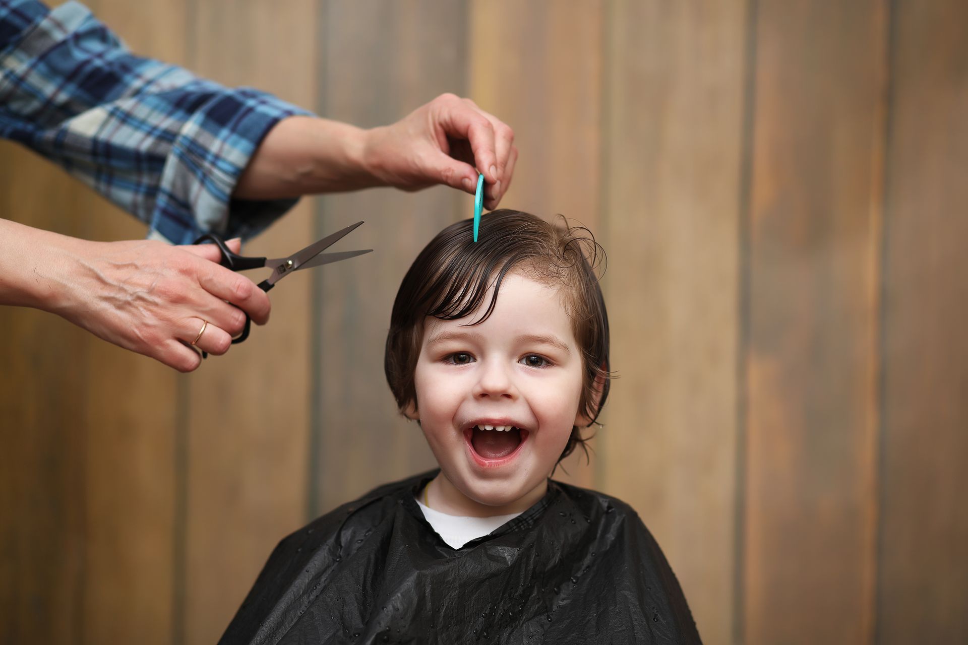 A little boy is getting his hair cut by a hairdresser.