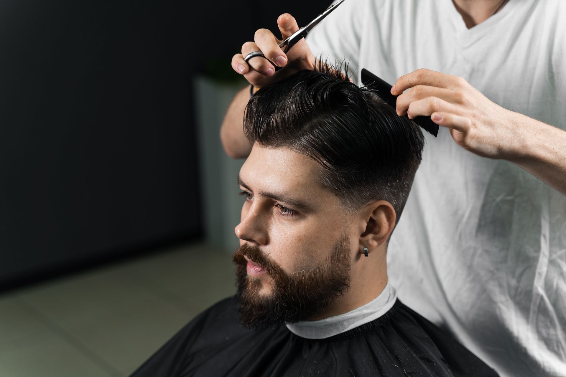 A man is getting his hair cut by a barber in a barber shop.