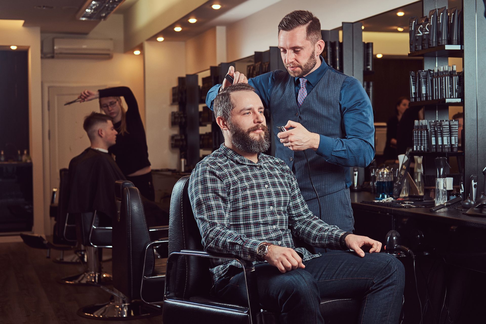 A man is getting his hair cut by a barber in a barber shop.