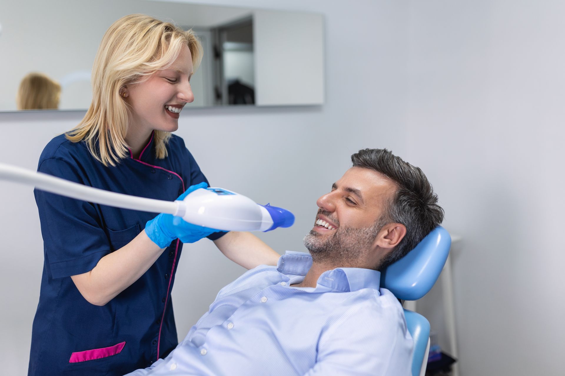 Dentist using whitening equipment on a patient in a dental office.