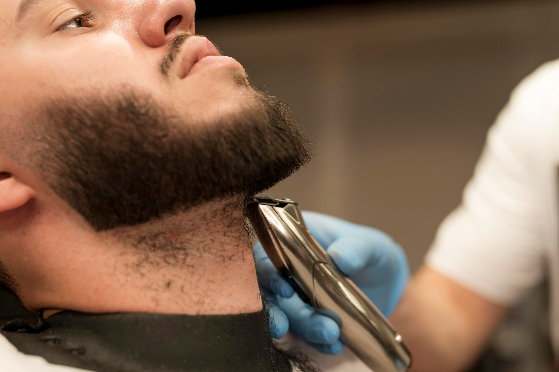 A man is getting his beard trimmed by a barber.