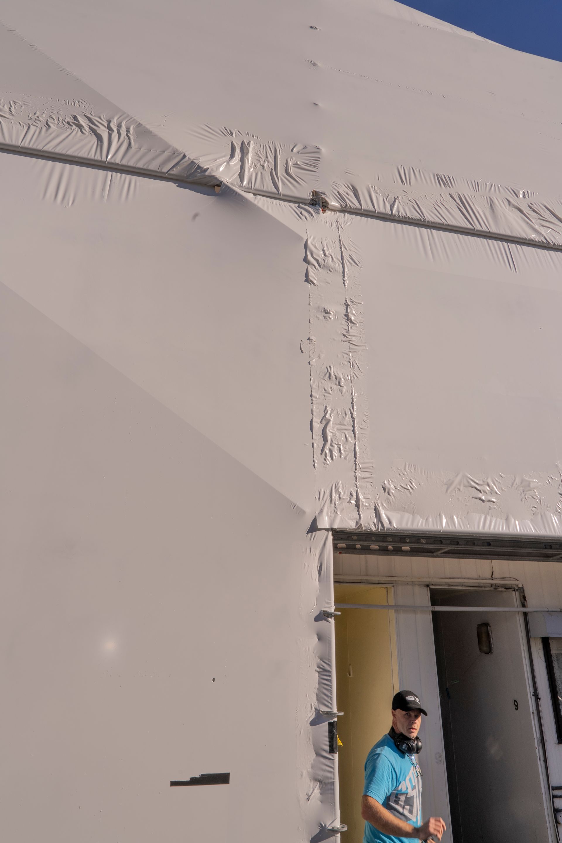 A man is standing in front of a white building.