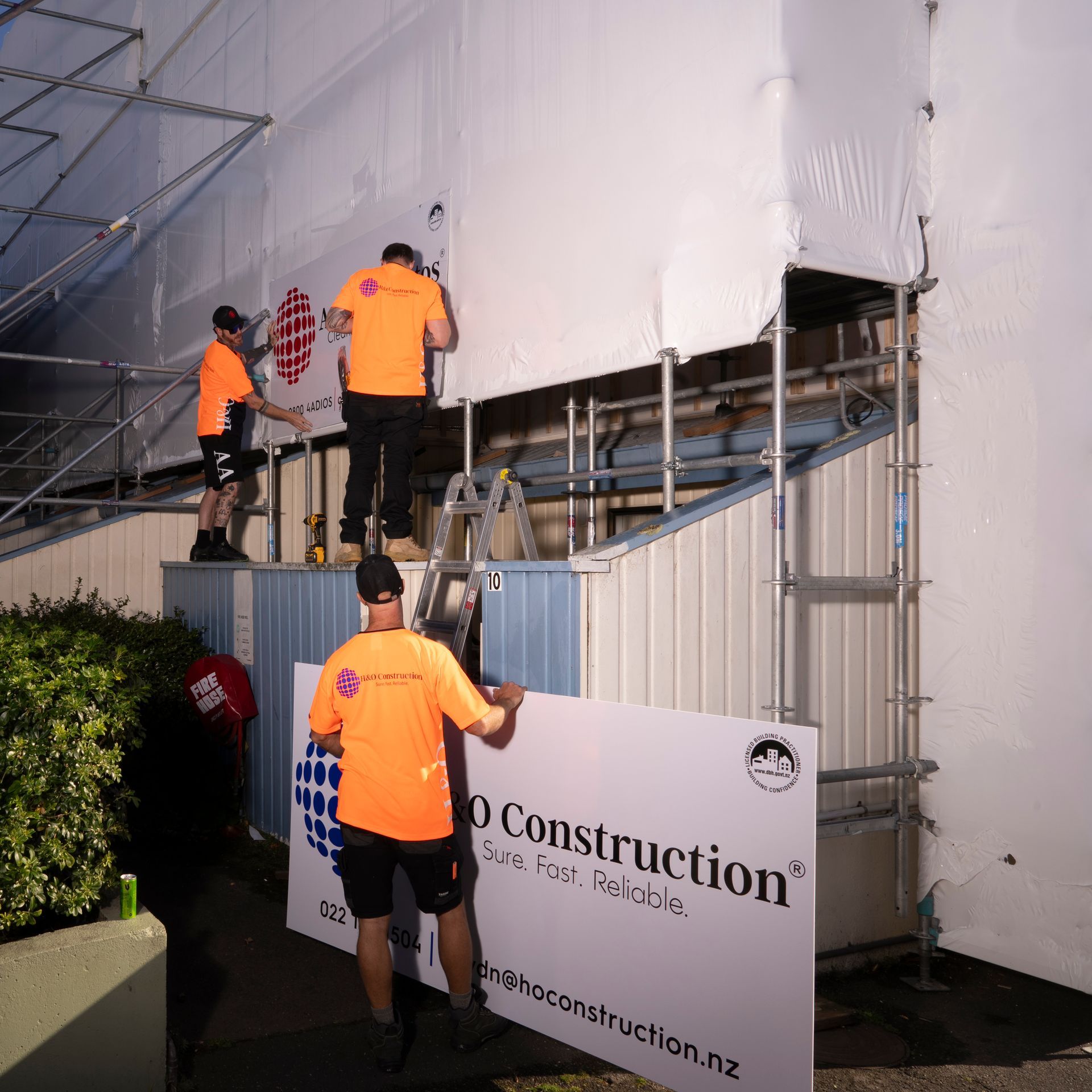 Construction Workers Adjusting Sign — Wellington, NZ — H & O Construction