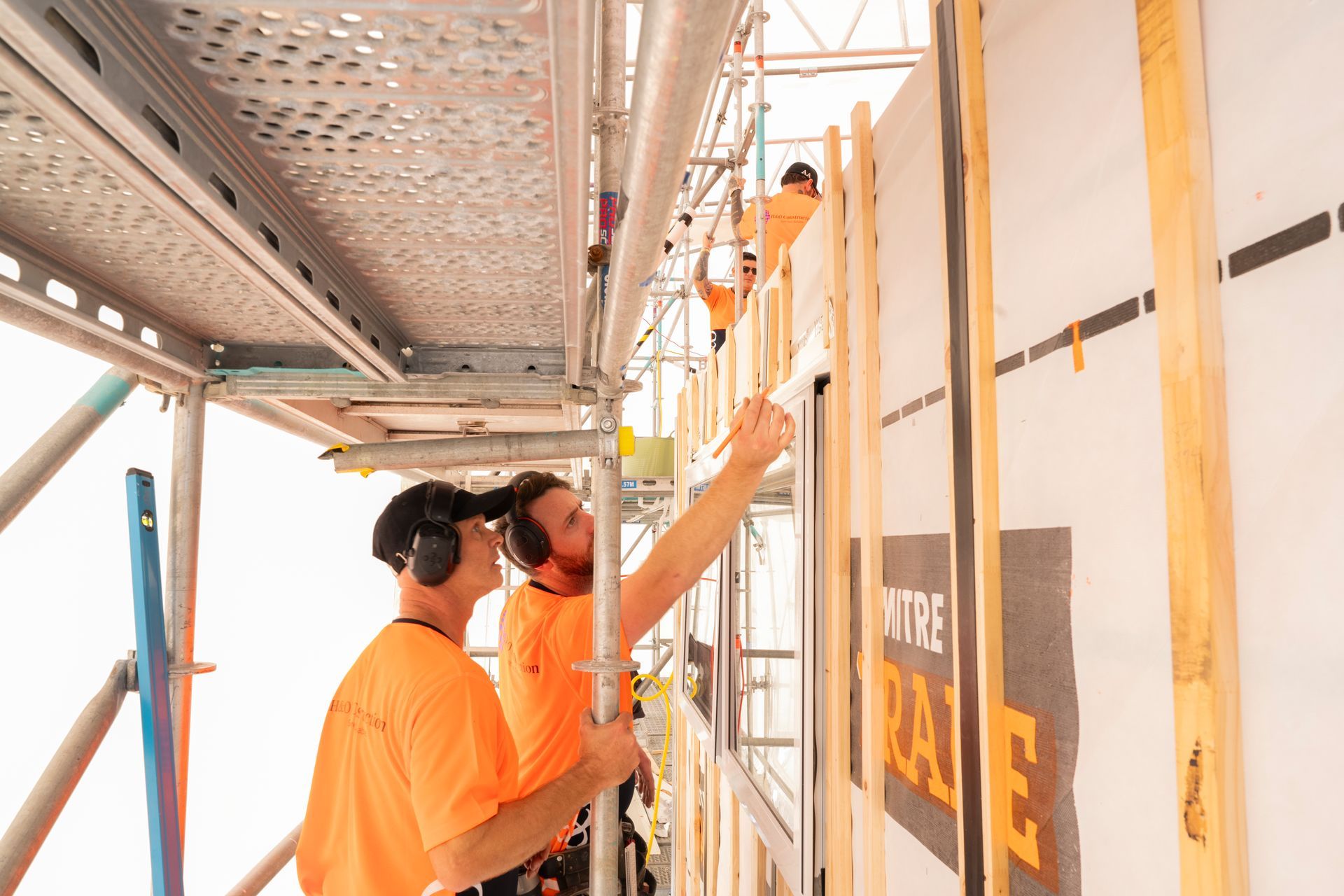 Two men are working on a building on a scaffolding.