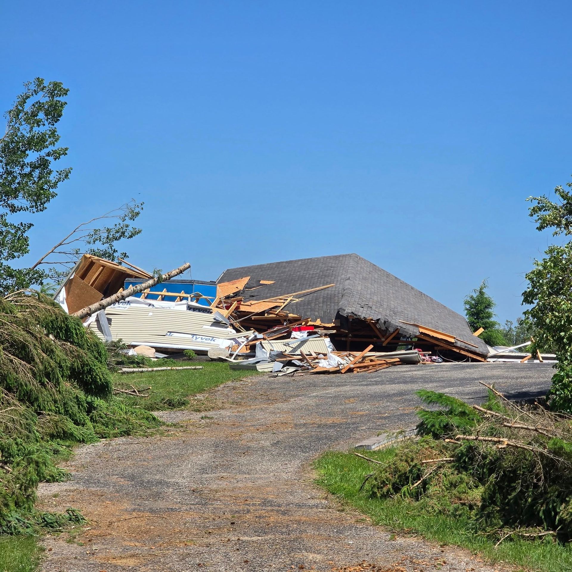 A destroyed building sits on a hill. Debris is scattered. Blue sky overhead.