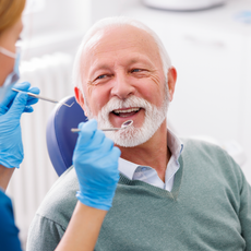 A man with a beard is getting his teeth examined by a dentist.