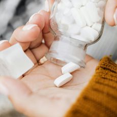 A person is pouring white pills into their hand