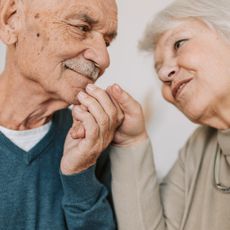 A man and a woman are holding hands and smiling at each other.