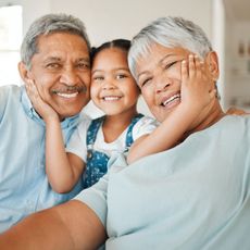 A man and woman are holding a little girl and smiling for the camera.