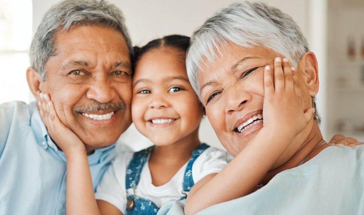 An elderly couple and a little girl are posing for a picture together.