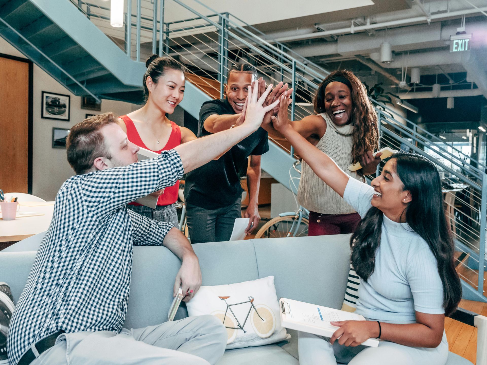 A group of people are giving each other a high five while sitting on a couch.
