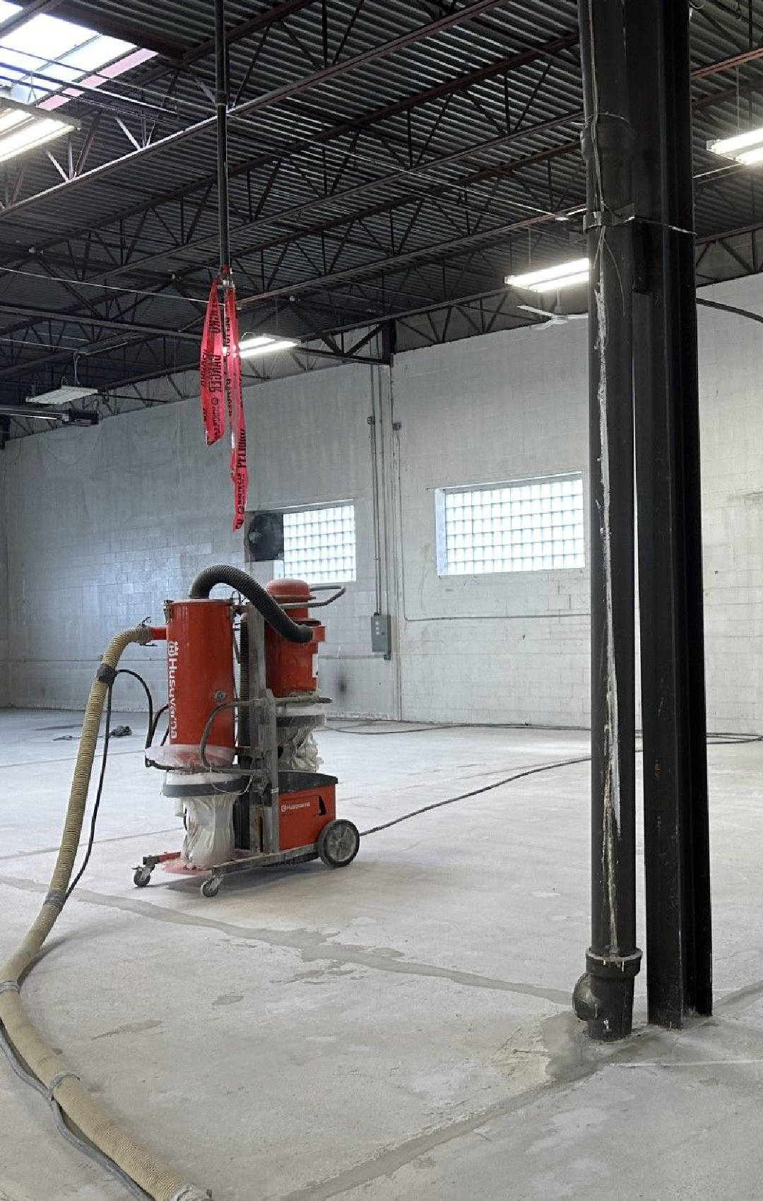 A concrete polishing machine is sitting in the middle of a large warehouse.