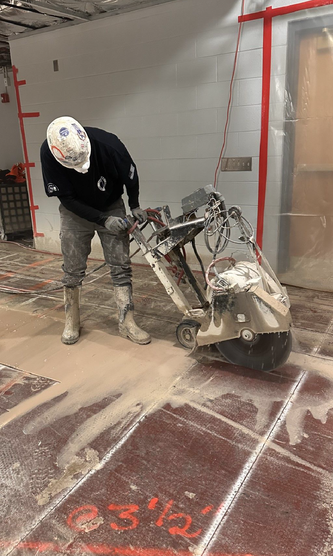 A man is using a slab sawing machine to cut a tile floor.