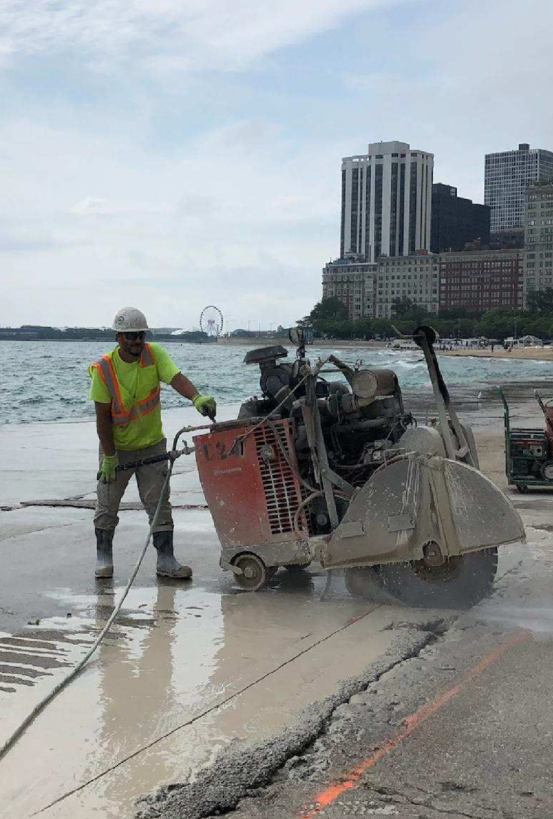A man is cutting concrete with a circular saw on the beach.