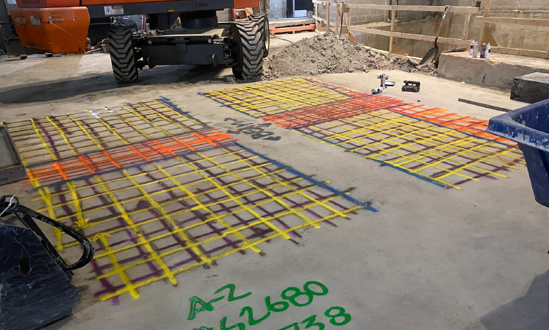 yellow, red, and green markings of underground utilities on a concrete slab