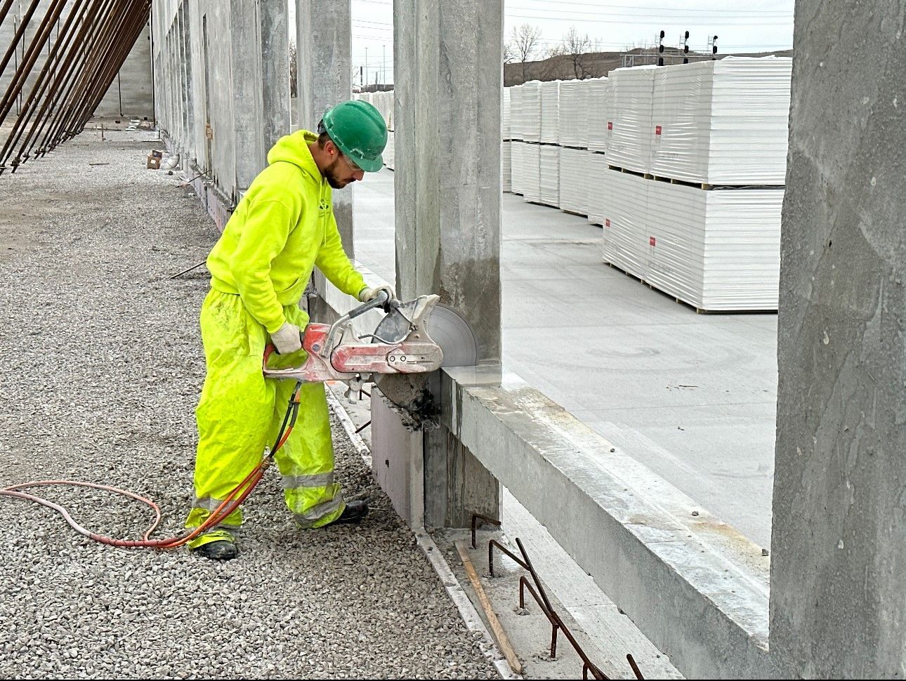 A construction worker is cutting a concrete wall with a saw.