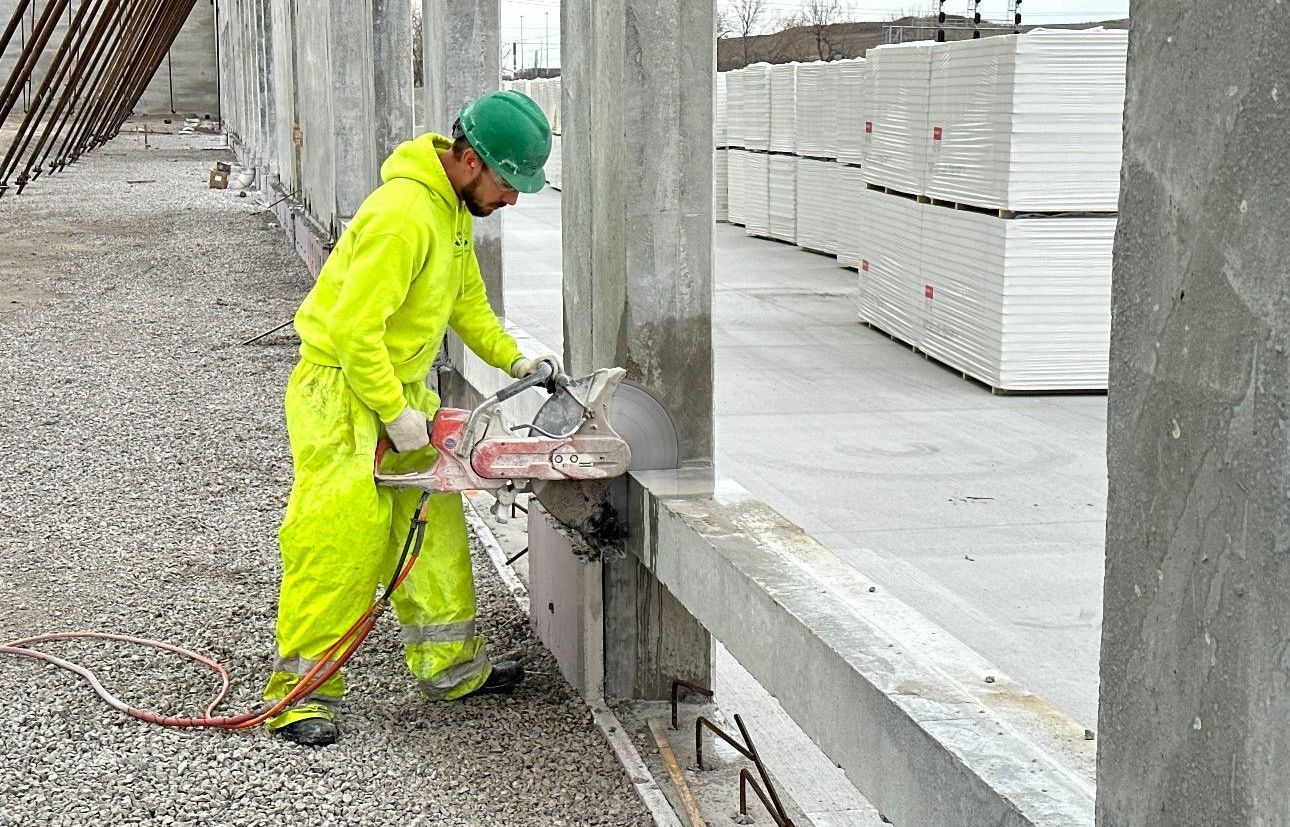 A construction worker is cutting a hole in a concrete wall with a saw.