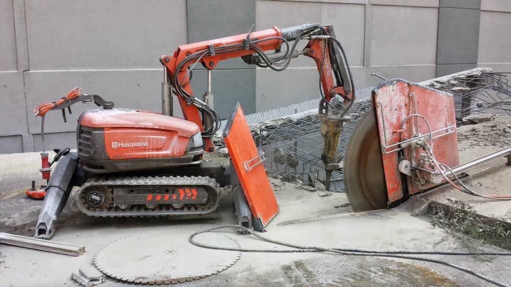 a concrete demolition site with slab sawing and breaking machines are running