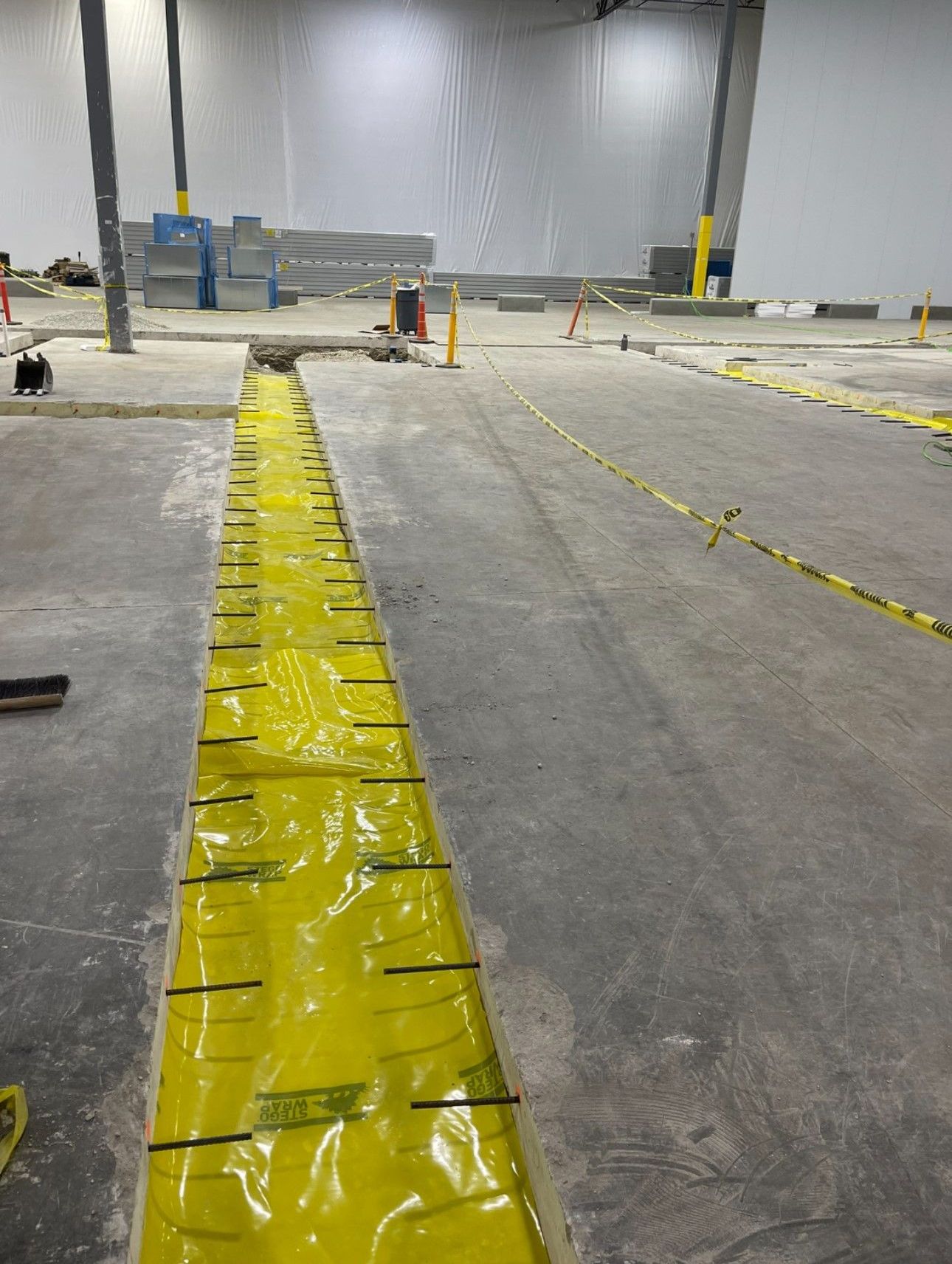 A large warehouse with a lot of yellow tape on the floor.
