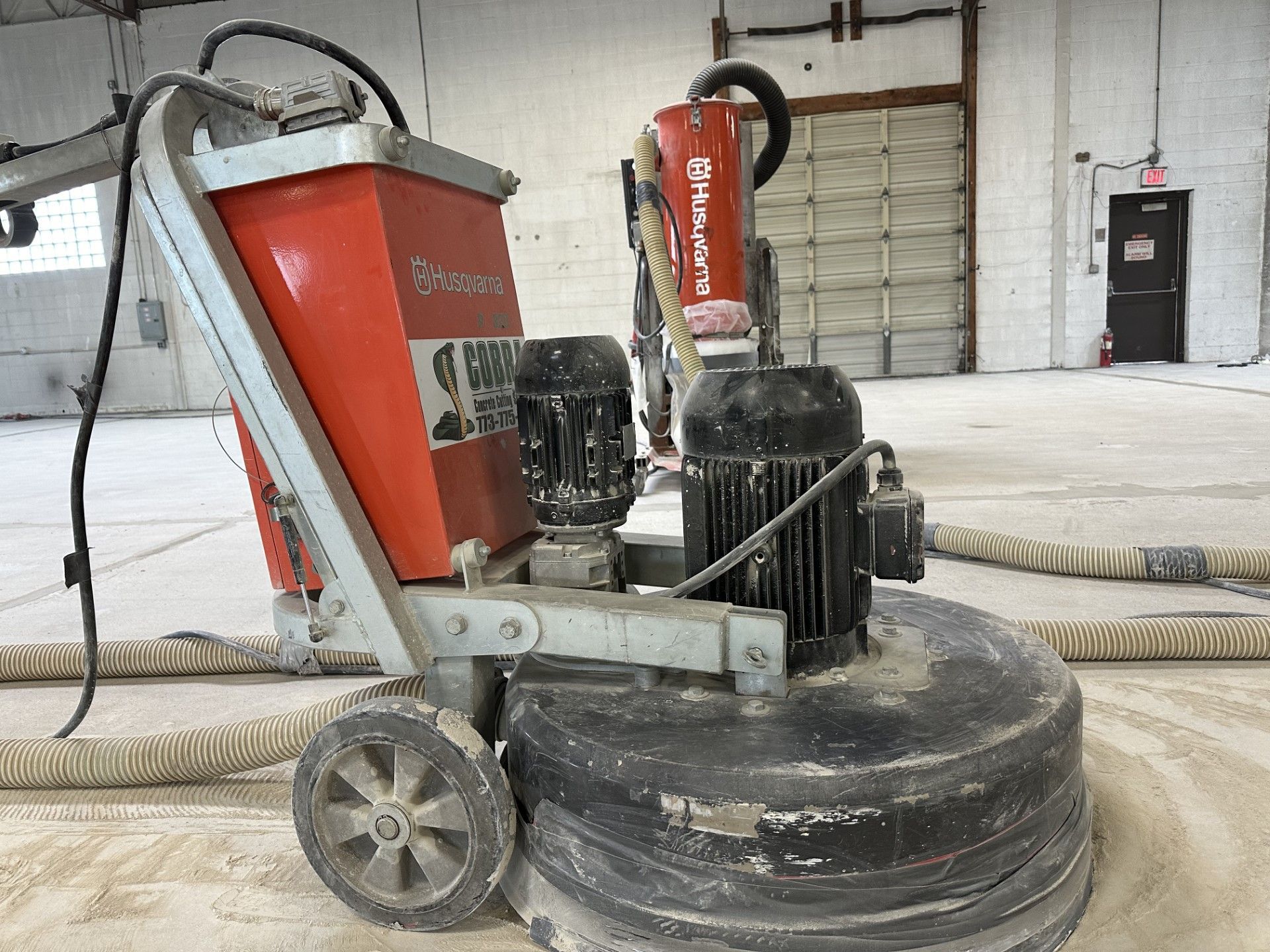 A concrete floor polishing machine is sitting on a concrete floor in a warehouse.