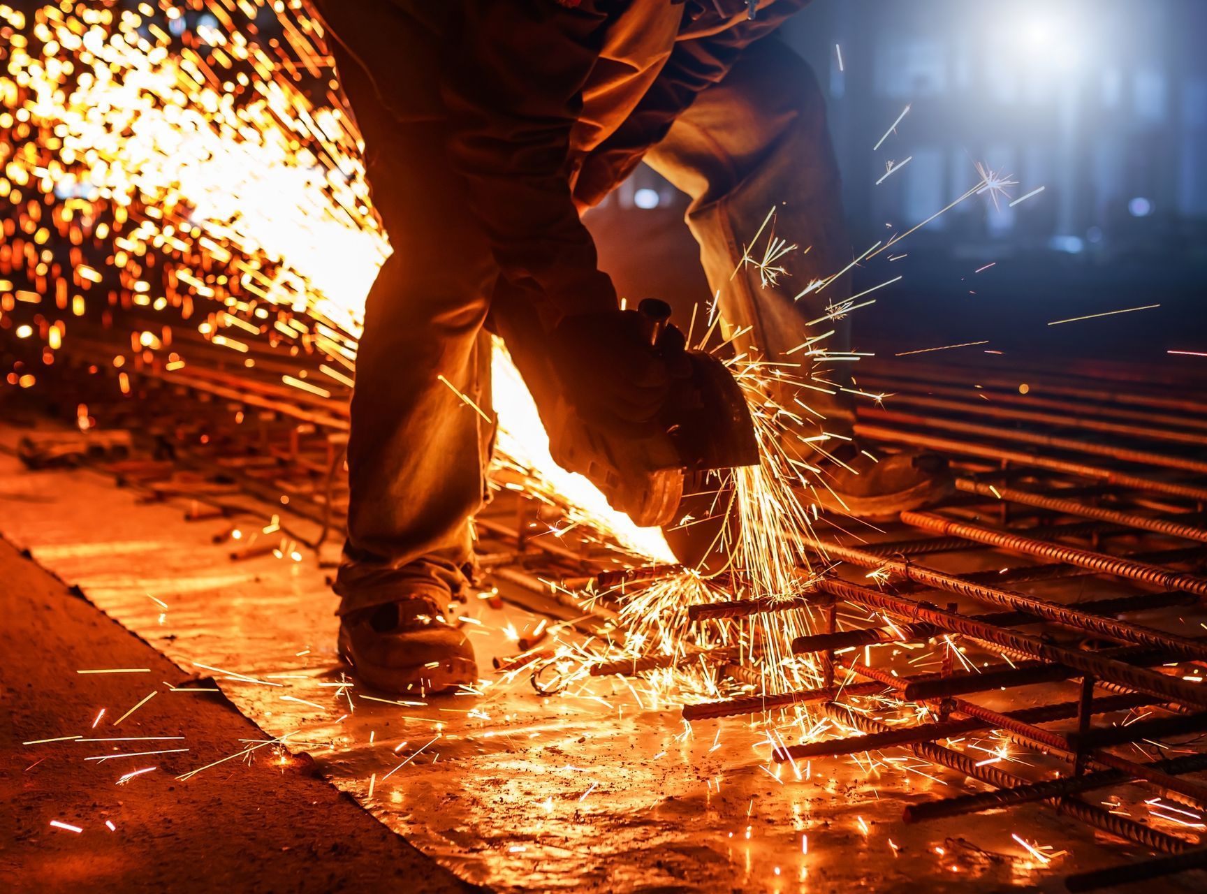 A man is cutting a piece of metal with a grinder.