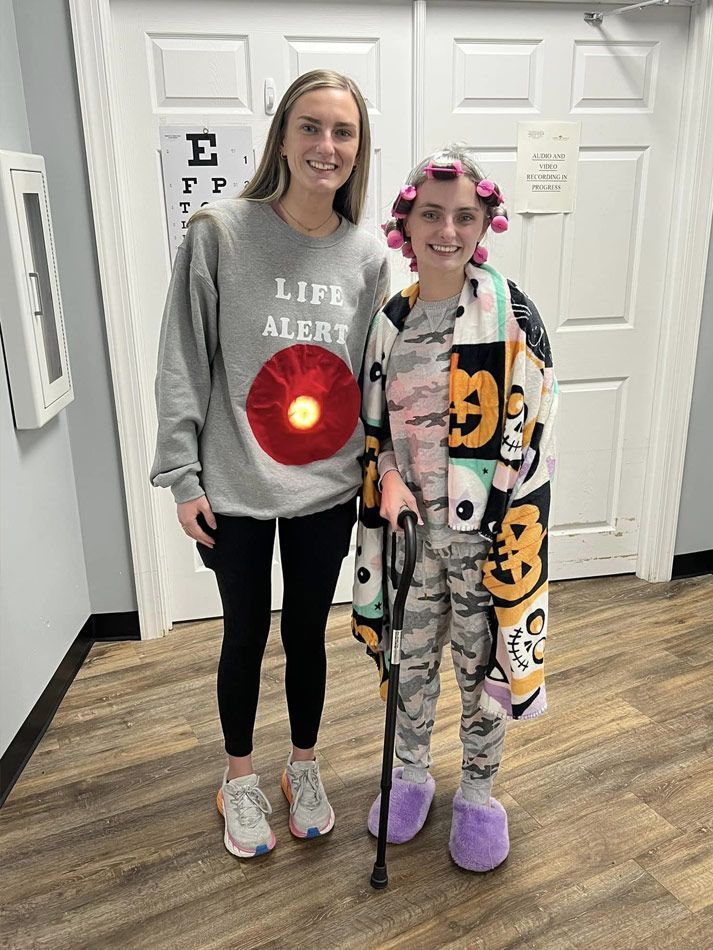 Two young women are standing next to each other in a hallway.
