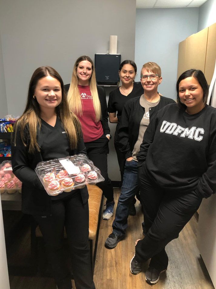A group of women are standing in a room holding a tray of cupcakes.