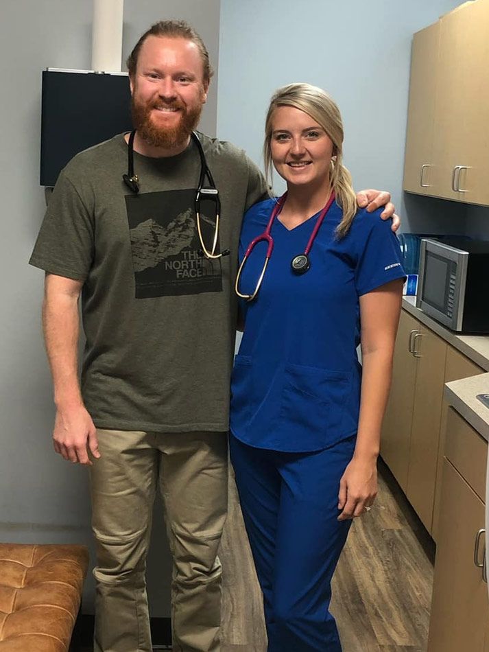 A man and a woman are posing for a picture in a kitchen.