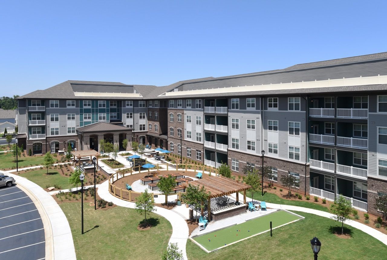 U-shaped apartment buildings surround a landscaped courtyard with seating, a pergola, and walkways.