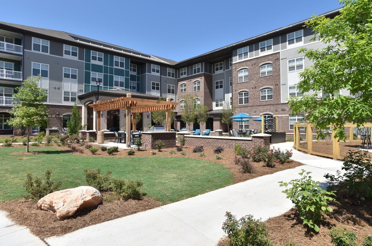 Exterior courtyard of apartment complex with pergola and seating.